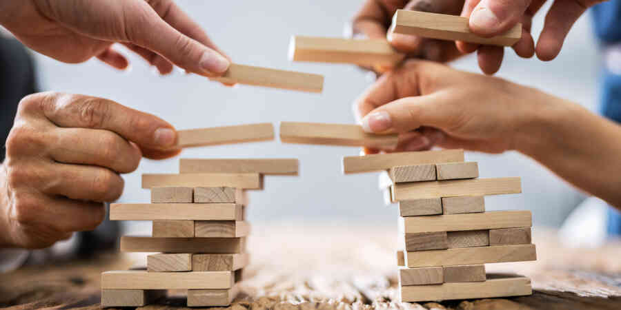 Hands Building a Bridge with Jenga Blocks Image