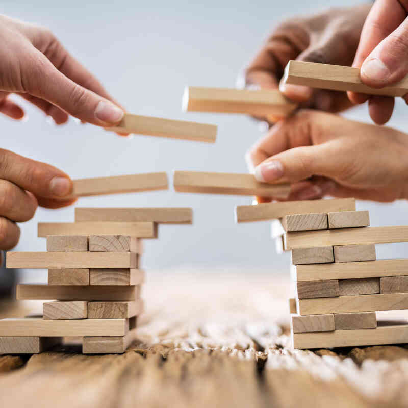 Hands Building a Bridge with Jenga Blocks Image